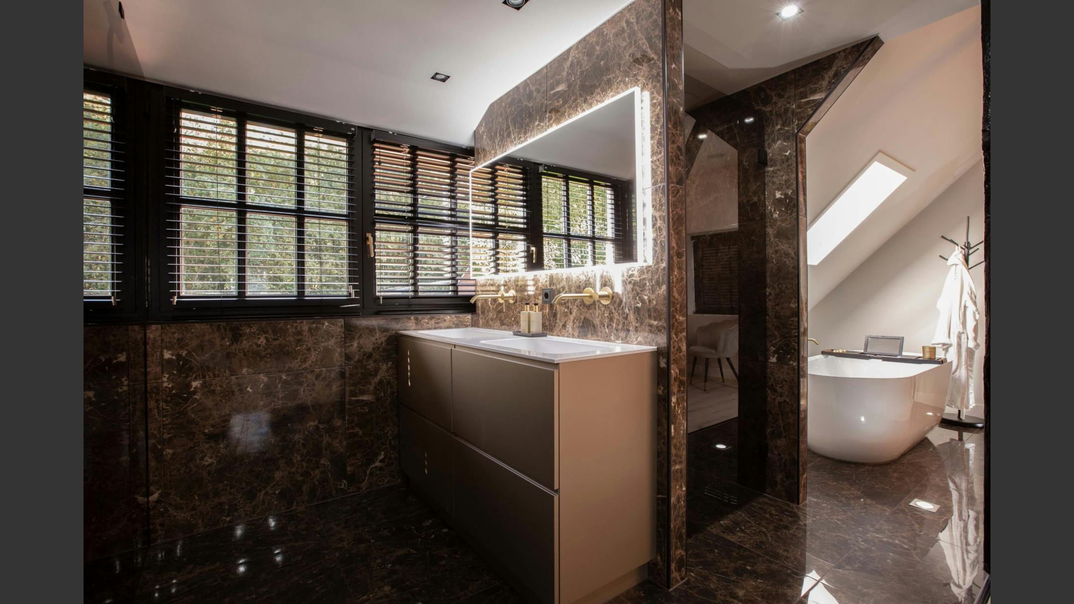 Unieke en exclusieve badkamer met bruin marmer en een verlichte spiegel